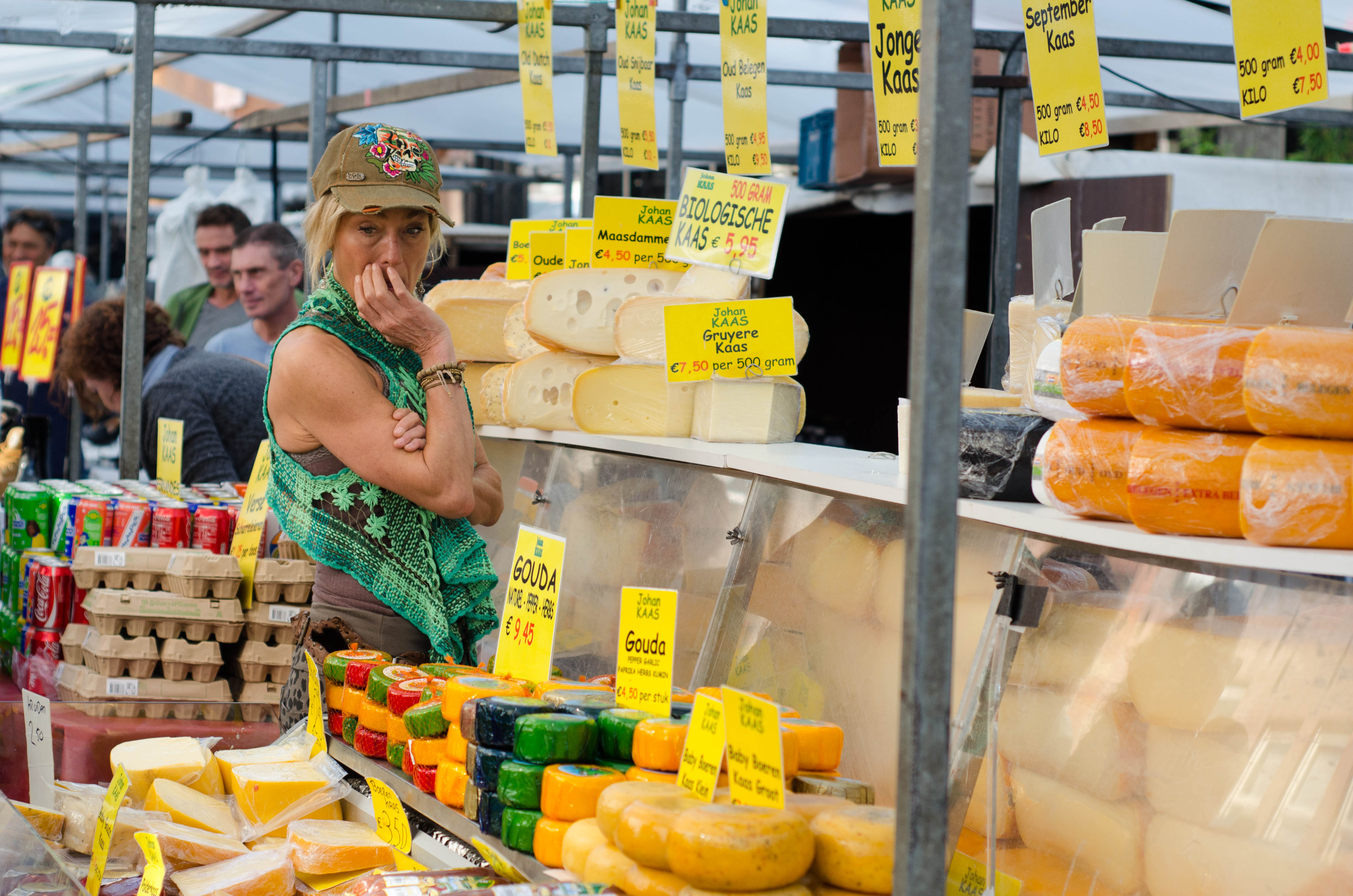 a Dutch woman ponders the many cheese options available for sale at the outdoor market in Amsterdam, Albert Cuypmarkt
