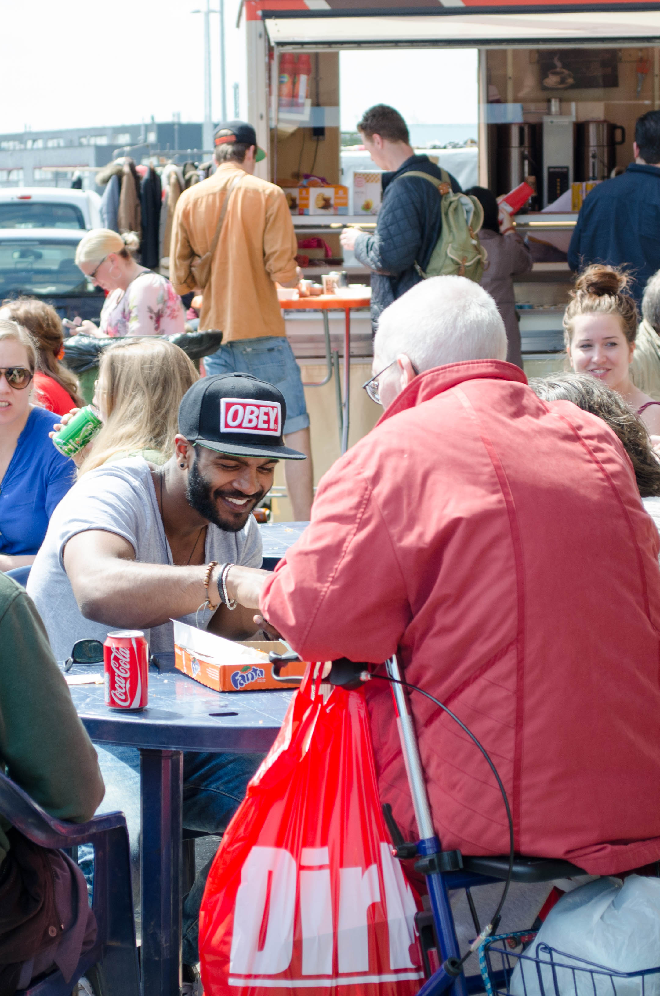 people enjoy the sun and food trucks outside the giant flea market, IJhallen in Amsterdam-Noord